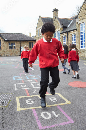 Bild auf Leinwand Group Of Children Playing Hopscotch In School Playground