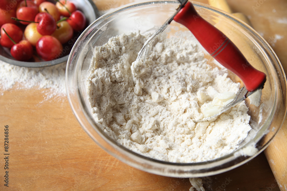 Cutting butter into flour to make pastry crust for cherry pie, copy space included