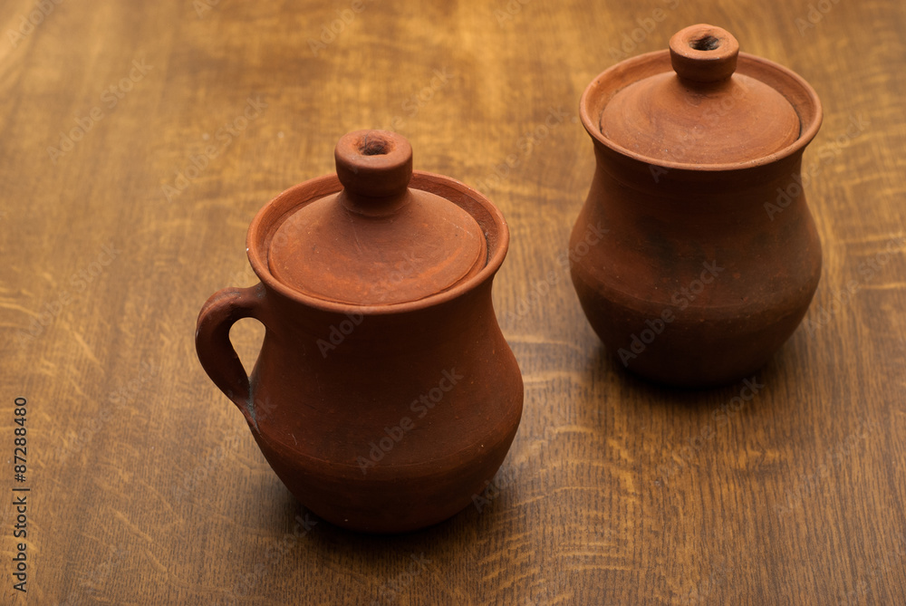 two clay pots on a wooden background