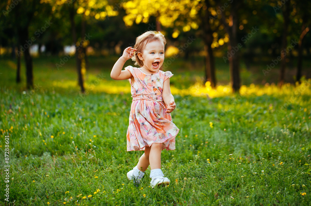 Happy cute little girl running on the grass in the park. Happine Happy cute little girl running on the grass in the park. Happine