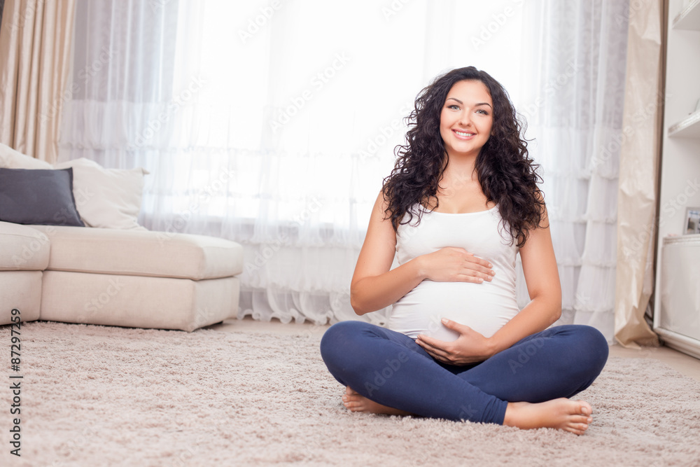Pregnant healthy woman is relaxing on flooring
