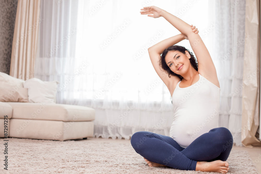 Pretty young expectant mother is exercising in bedroom Pretty young expectant mother is exercising in bedroom
