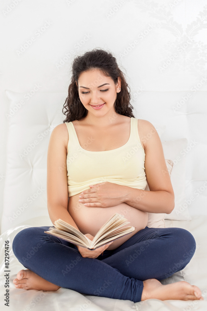 Cheerful young pregnant woman is resting in bedroom Cheerful young pregnant woman is resting in bedroom