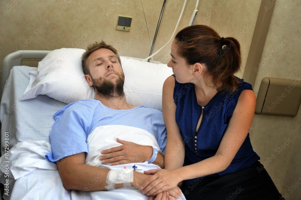 couple at hospital room man in bed and woman holding hand caring couple at hospital room man in bed and woman holding hand caring