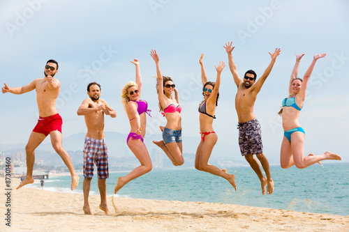 Happy tourists jumping on beach