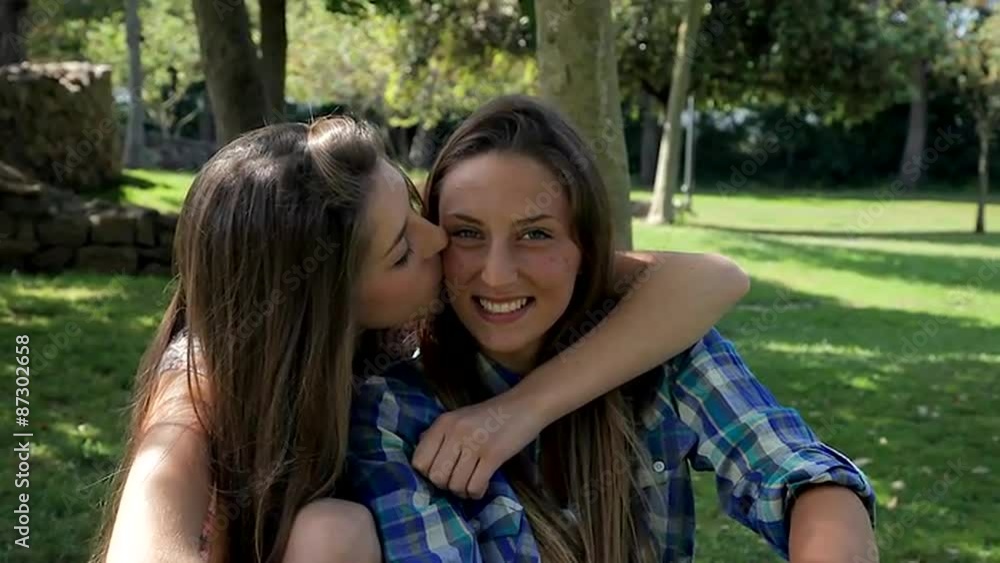 Portrait of two happy teenager hugging and kissing looking camera Portrait of two happy teenager hugging and kissing looking camera