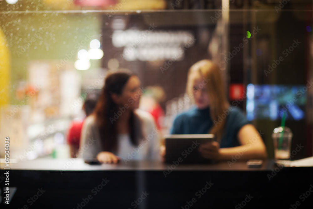 Fototapeta premium Two female friends using tablet PC in a cafe