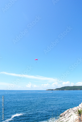 Paragliding above blue sea on a sunny day. Summer seascape. Concept of freedom and adventure.