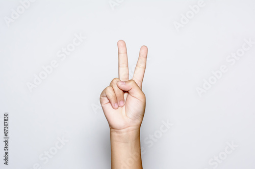 Fototapeta Chlapec zvyšování dvou prstů nahoru na stranu je to ukazuje míru sílu bojovat, nebo vítězství symbol a písmeno V ve znakovém jazyce na bílém pozadí