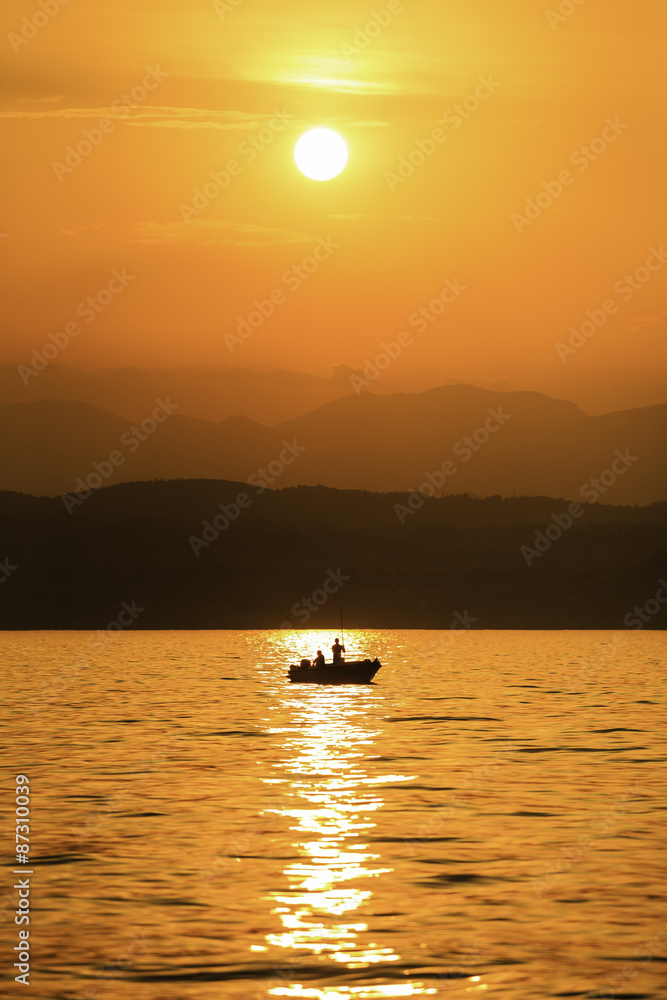 man fishing at vibrant colorful sunset over lake