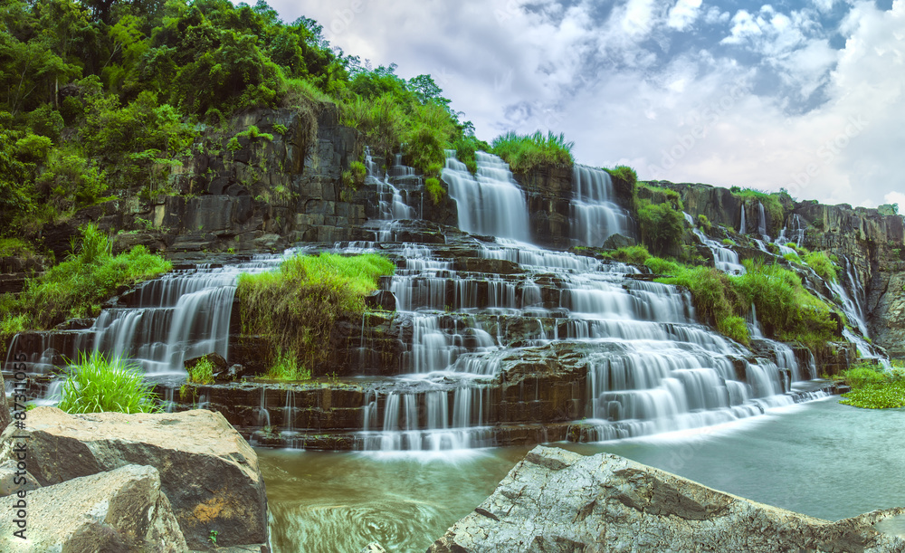 Obraz premium Pongour on summer days with many storied stone structure water flowing in the great stone steps. First waterfall in Lam Dong is here