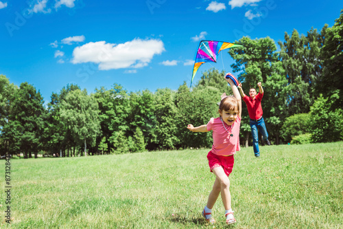The girl and her father play with a kite.