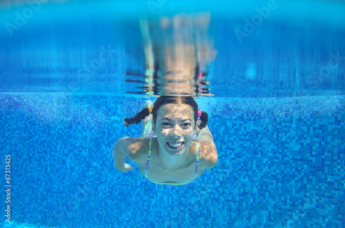 Happy child swims in pool underwater, active kid swimming, playing and having fun