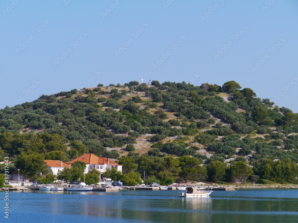 The village Murter on the island Murter in the Adriatic sea of Croatia with a blue and white fishing boat in front