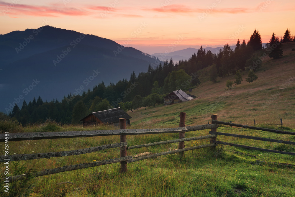 Fence in mountain valley. Agricultural landscape during sunrise.