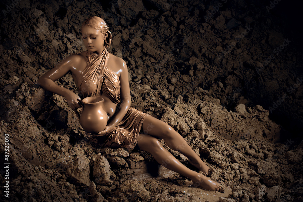 Fashion portrait of a beautiful young woman smeared with clay holding an ancient pot Fashion portrait of a beautiful young woman smeared with clay holding an ancient pot