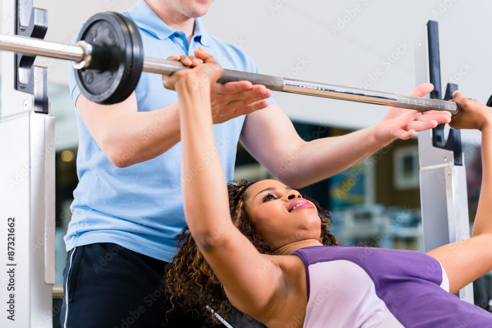 Black woman with Trainer lifting weights in gym for fitness Black woman with Trainer lifting weights in gym for fitness