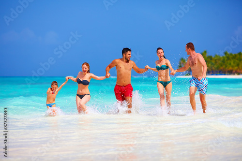 group of happy friends running together on tropical beach © Olesia Bilkei