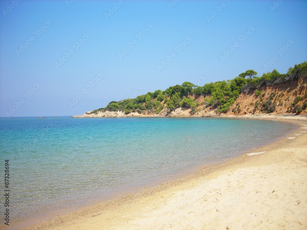 Transparent blue waters of the Mandraki beach on the Greek island of Skiathos, on a sunny summer day.
