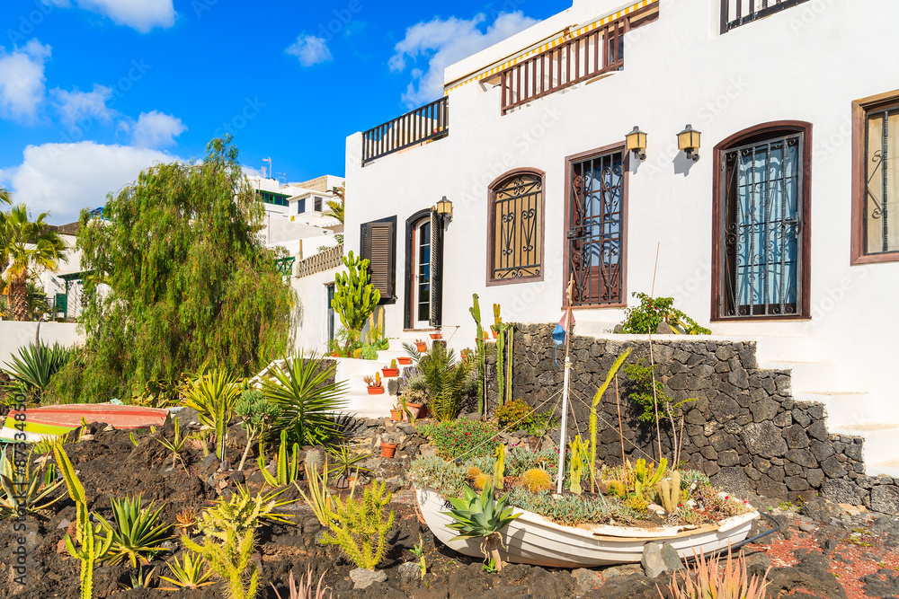 Fishing boat in garden of typical Canarian houses in Puerto del Carmen town on coast of Lanzarote island, Spain