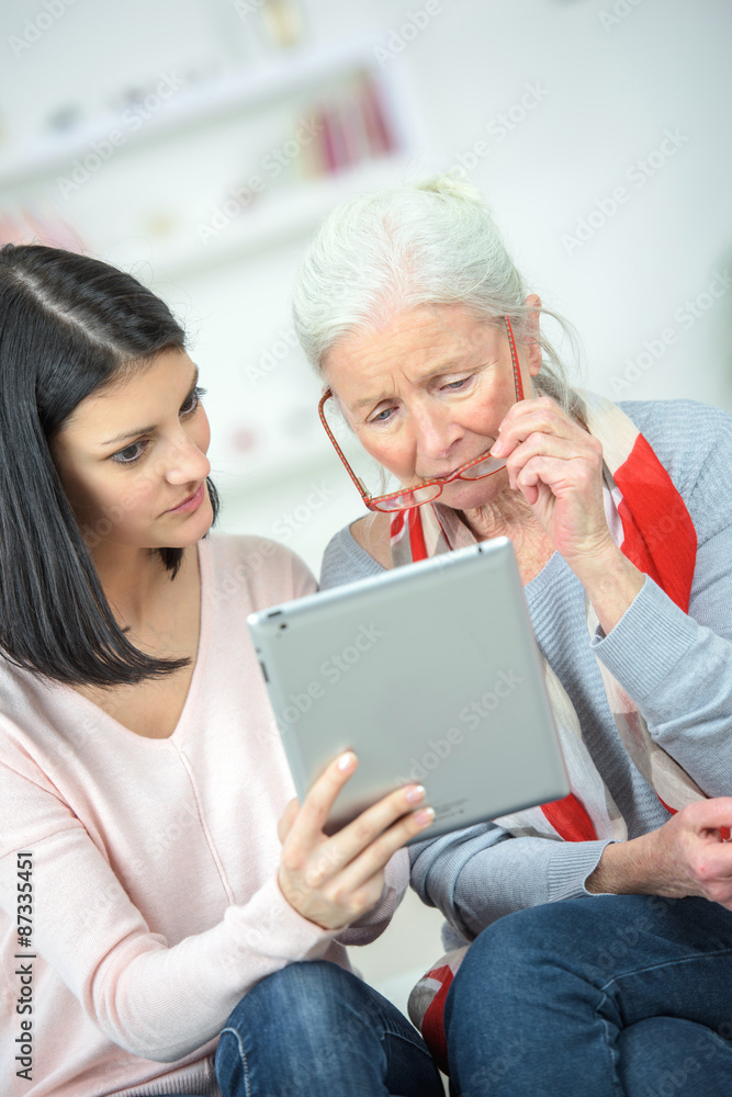 Helping old woman use a tablet computer Helping old woman use a tablet computer
