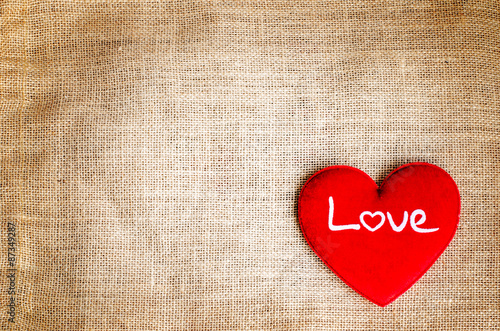 Red heart with love text on gunny sackcloth texture background