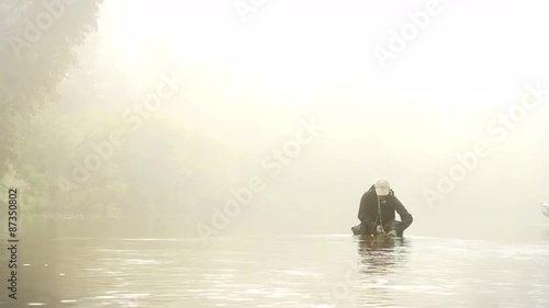 Man Dehooking a Fish in a River Enveloped by Fog photo