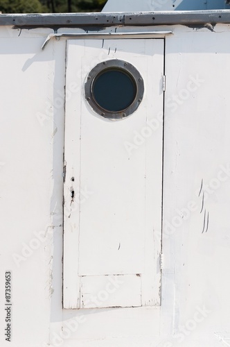 Old white wooden door on the ship with a circular window