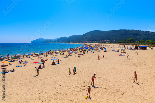 Beach of the Cantabrian coast with tourists with sunbeds and umbrellas on the hot summer day