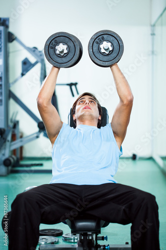 Man exercising in gym, using weights