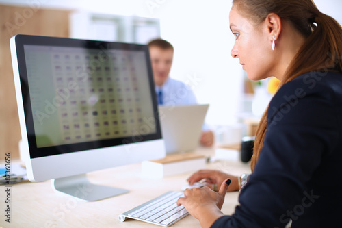 Young woman working in office, sitting at desk, using laptop
