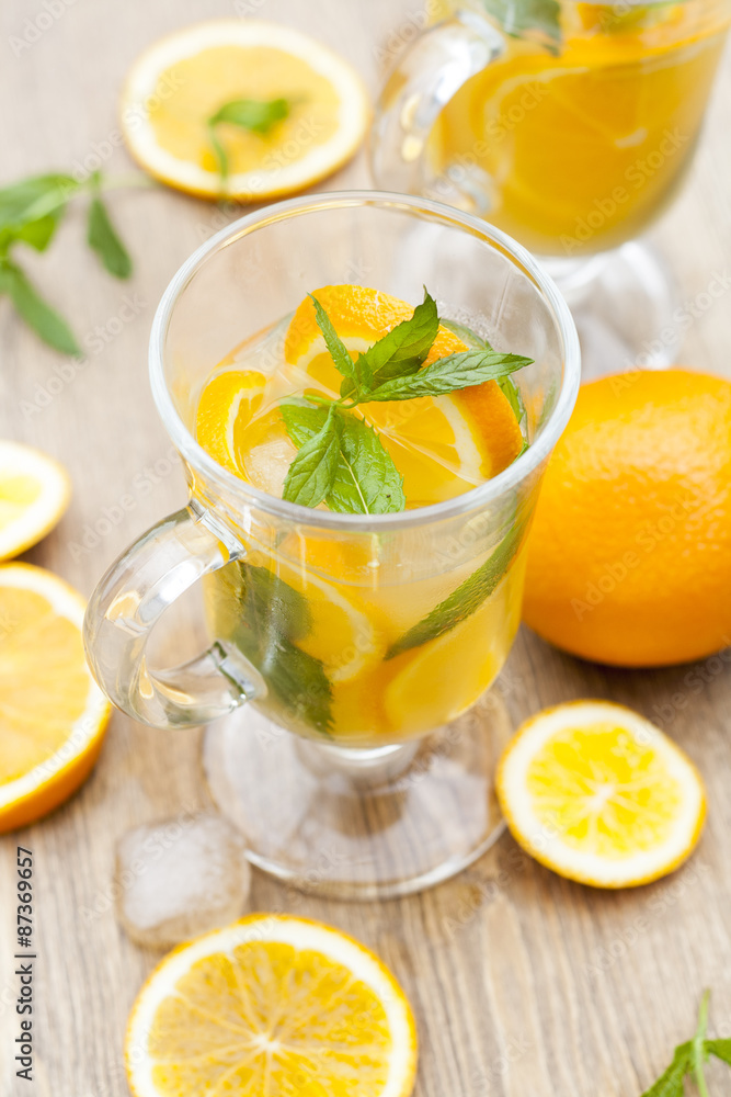Orange fresh drinks with ice and mint on wooden table, selective focus Orange fresh drinks with ice and mint on wooden table, selective focus