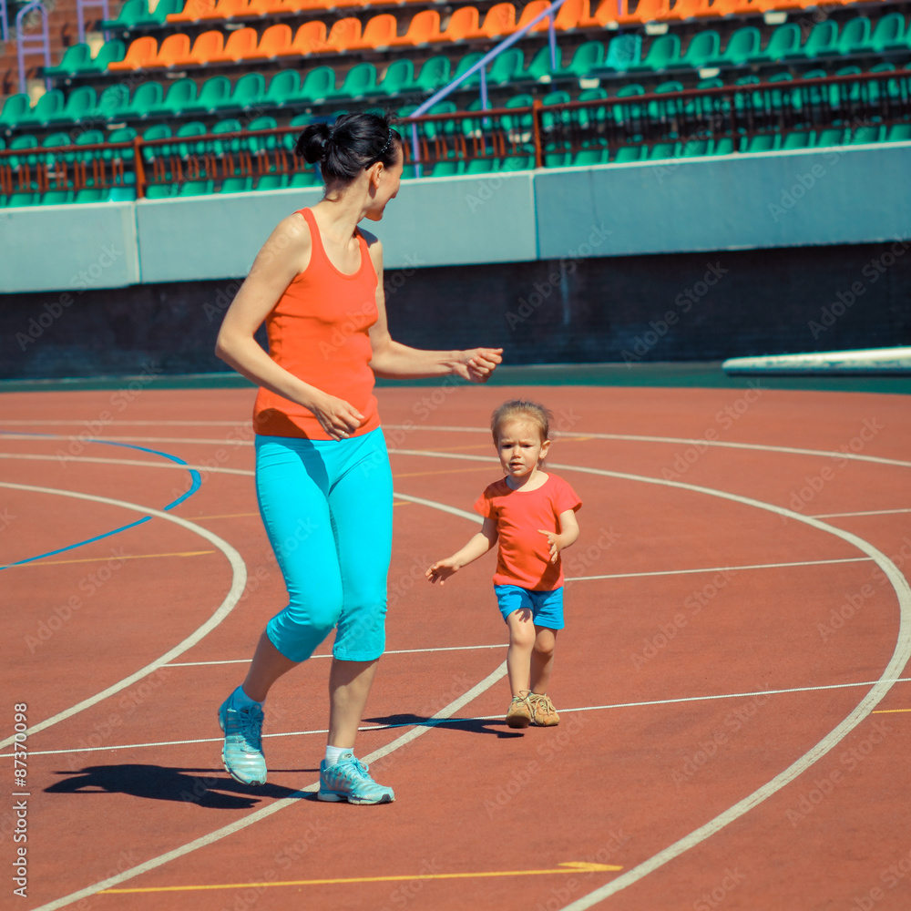 Mother & little daughter running around the stadium. Child runs away from mom at the stadium.