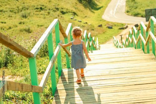 Little girl walking down stairs. View from the back.