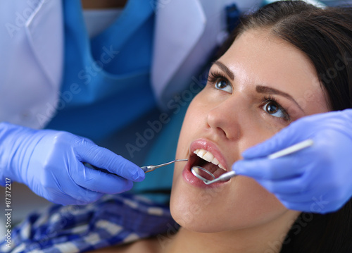 Woman dentist working at her patient teeth