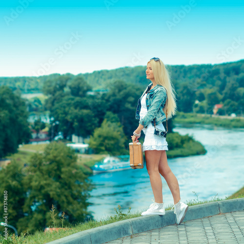 Hipster girl with vintage suitcase on the urban landscape. portrait of a beautiful blonde