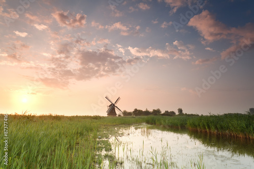 sunrise over windmill by river