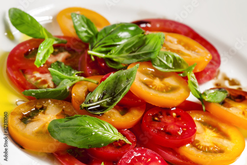 Vegetable salad of colorful tomatoes and basil with olive oil an