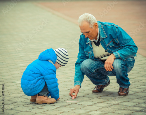 Grandfather and grandson draw with chalk on the road