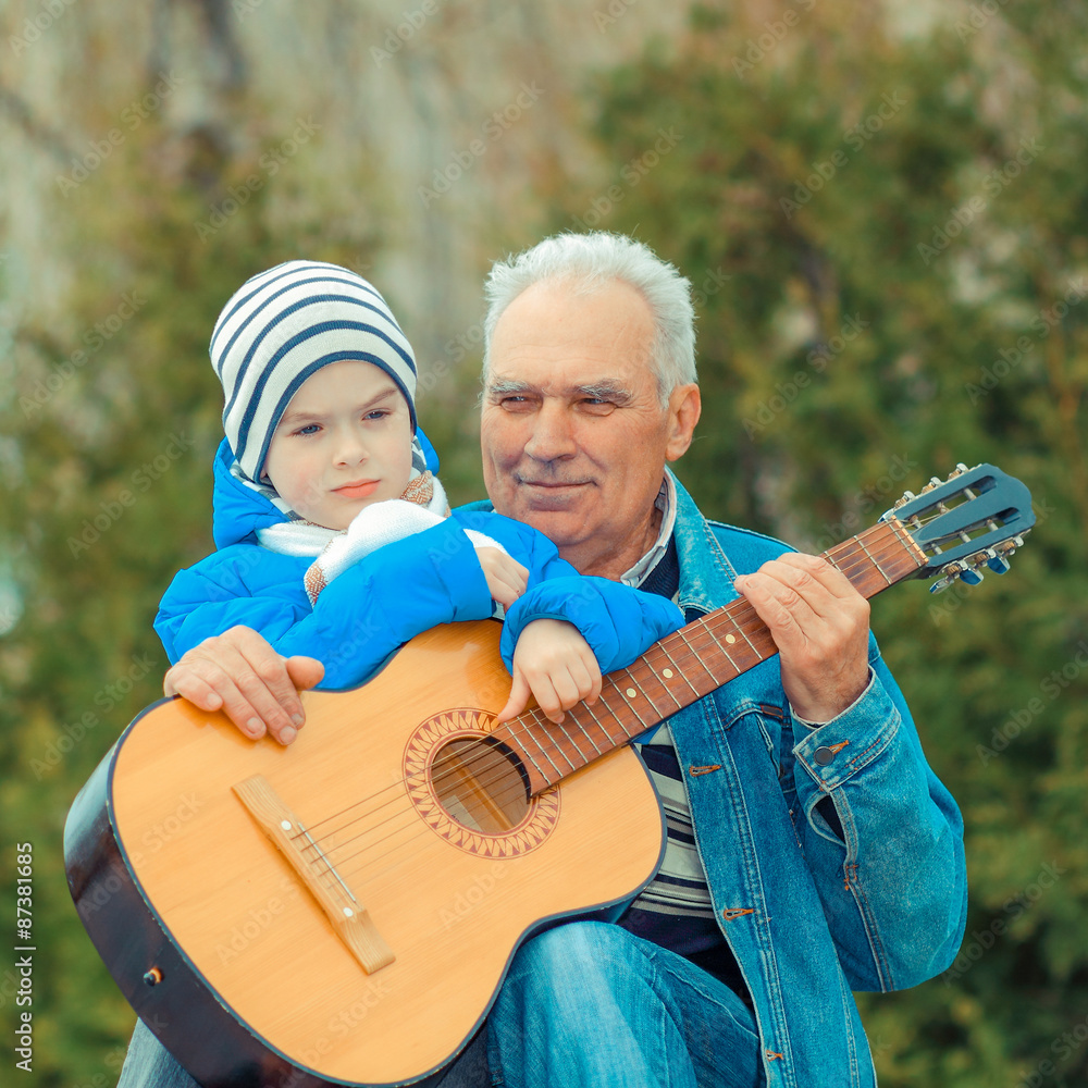 Grandfather and grandson playing guitar outdoors