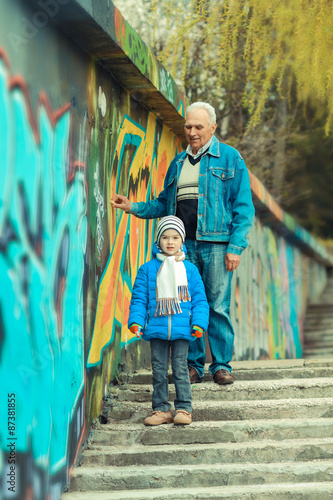 Grandfather and grandson paint graffiti on the wall