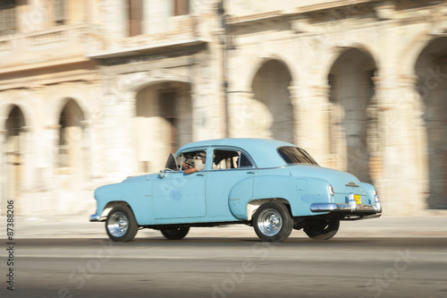 Vintage blue American car taxi driving in front of classic colonial architecture on the Malecon in Central Havana © lazyllama