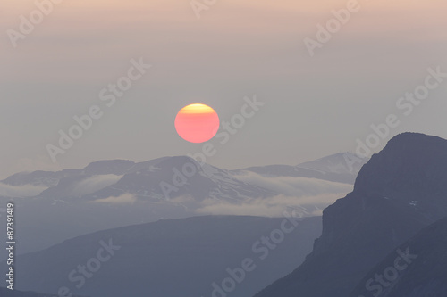 Obraz na plátně Huge red midnight sun above mountain range