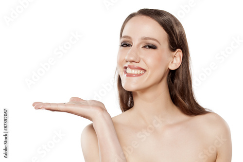 young smiling woman advertises imaginary object