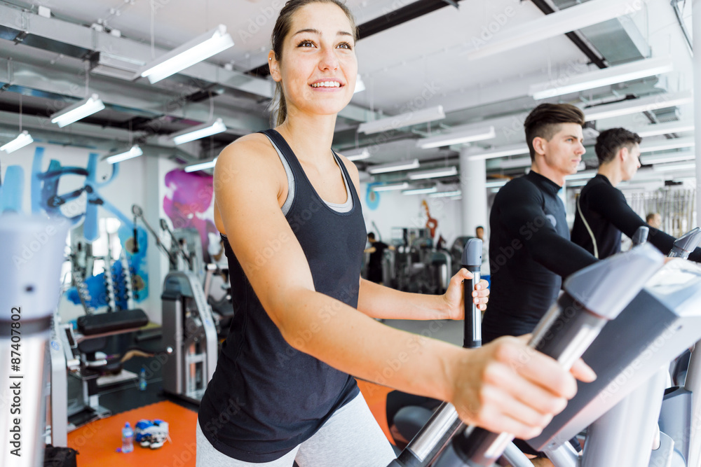 Fototapeta premium Young fit woman using an elliptic trainer