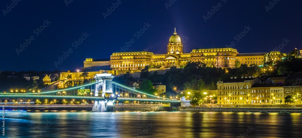 Fototapeta premium Night view over illuminated complex of buda castle in budapest taken from opposite shore of danube river.