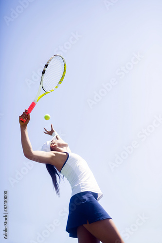 Beautiful female tennis player serving