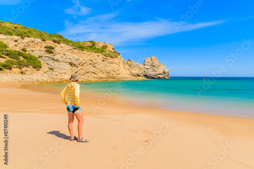 Young woman tourist standing on beautiful sandy beach in Algarve region, Portugal