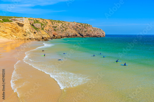 Surfers on Praia do Zavial beach with turquoise sea water, Algarve region, Portugal