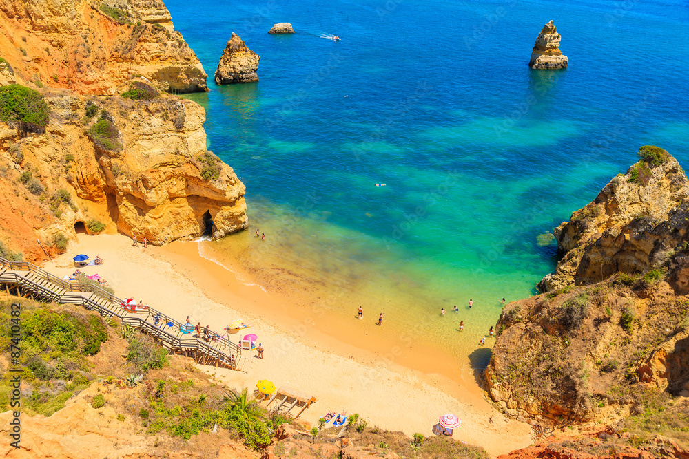 Turquoise sea water at Camilo beach with rock cliffs, Algarve region, Portugal